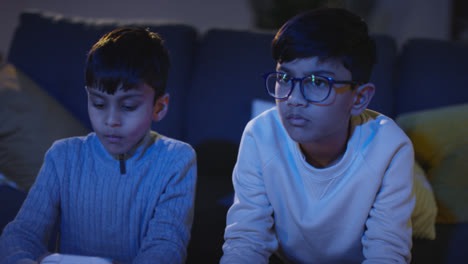 Front-View-Of-Two-Young-Boys-At-Home-Having-Fun-Playing-With-Computer-Games-Console-On-TV-Holding-Controllers-Late-At-Night-4